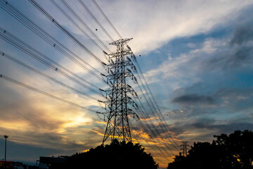 High voltage pole silhouette on sunset sky background.