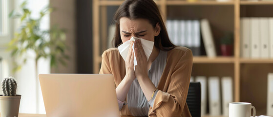 Ill office worker sneezing while facing the laptop, showing signs of flu.