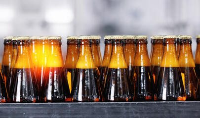 Beer brewery industry manufacturing. Brown glass bottles on conveyor belt, clean modern equipment.