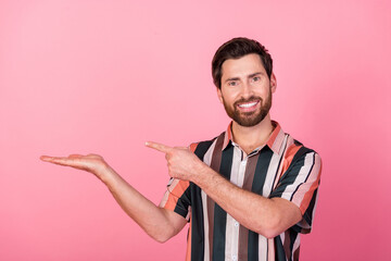 Photo of young optimistic influencer blogger man hand hold indicating sports product advert isolated on pastel pink color background
