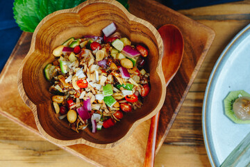 A bowl of food with a spoon in it sits on a wooden table