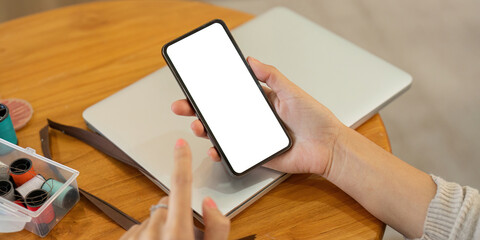 Mockup smartphone of a woman holding and using mobile phone with blank screen while on the sofa with feeling relaxed