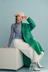 Fashionable confident woman wearing beret, elegant green coat, turtleneck, layered pearl necklace,...