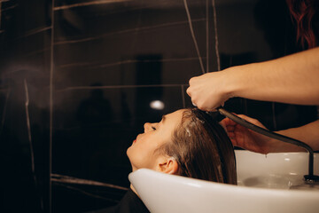 hairdresser washing client's hair at salon. happy young women customer relax and comfortable while...