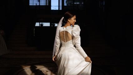 A young brunette in a white dress dances in the sun. Young woman in a dress. Turkish bride, close-up of face. A beautiful bride under a veil dances in the rays of the sun.