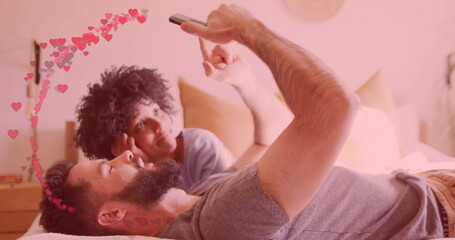 Image of hearts ove diverse couple using smartphone