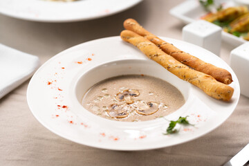 Mushroom champignon soup with breadsticks and fresh mushrooms in white plate. autumn seasonal cream soup