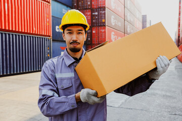 Handsome japanese male worker works shipping container warehouse carrying cardboard boxes packed...