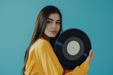Cheerful young woman holding a vinyl record on a blue background