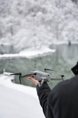 Drone dans le bras du pilote prêt au décollage dans un lac de montagne enneigé