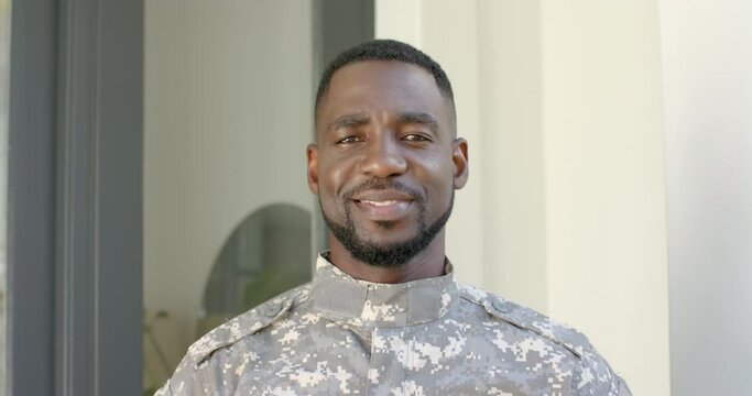 African American soldier in military uniform smiles warmly at home