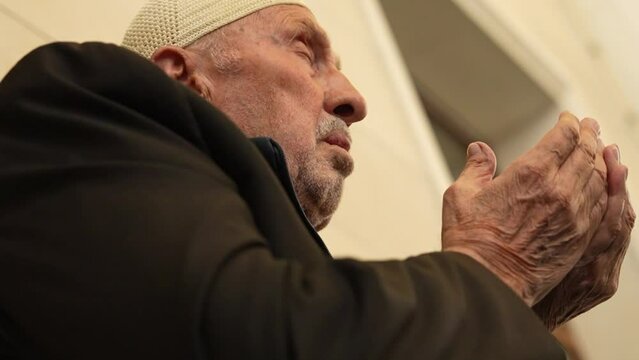 Old Muslim man with a prayer cap praying to Allah at Mosque in Ramadan month

