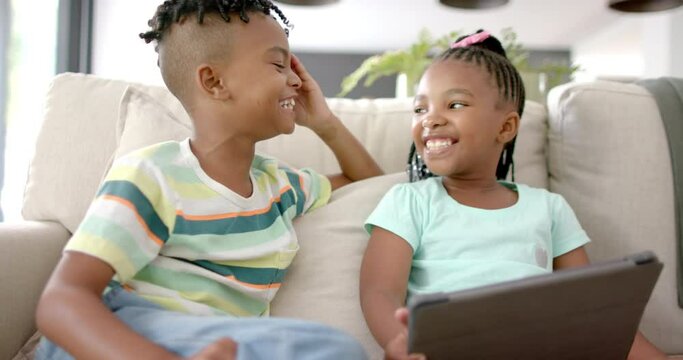 African American brother and sister share a joyful moment with a tablet at home
