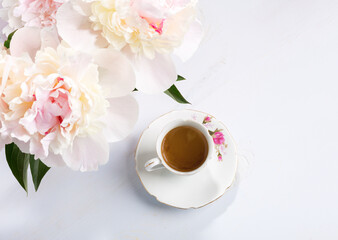 Small bouquet of peonies  and old porcelain cup with coffee  on a light lilac wooden table. Flat lay - 751373306