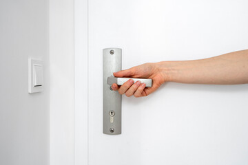 Cropped shot of female hand hold metal handle with keyhole and opening door