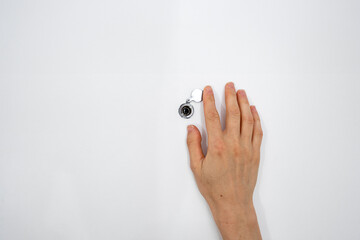 Cropped shot of woman watching through peephole at front door in apartment