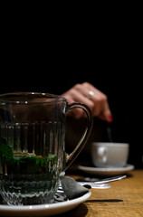 A woman's hand reaching out of the darkness to stir a cup of coffee
