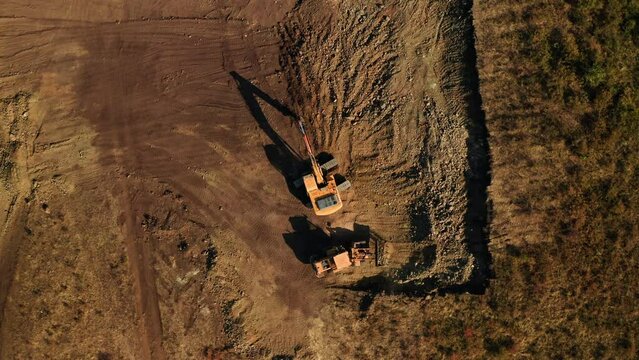 Top view of two excavators doing earthwork at construction site. Dig works from above