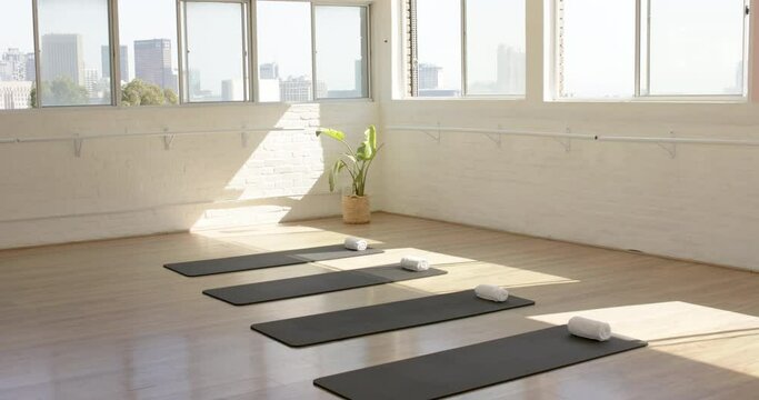 A serene yoga studio is set with four mats and towels under natural light, with copy space