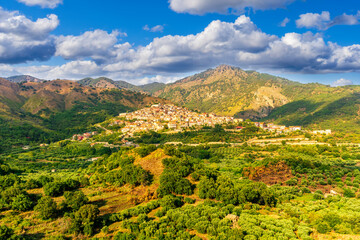 amazing mountain landscape with old yellow italian town among green beatiful mountains and cloudy sky above