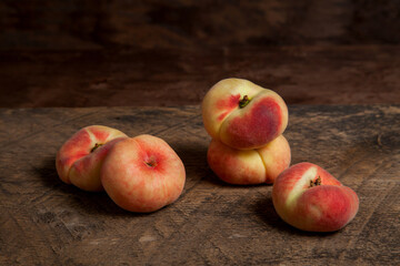 Several saturn peaches or flat peaches on wooden background..