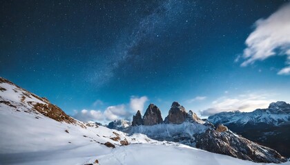 starry sky over snowy mountains at night in winter beautiful landscape with snow covered rocks blue clouds and star mountain valley