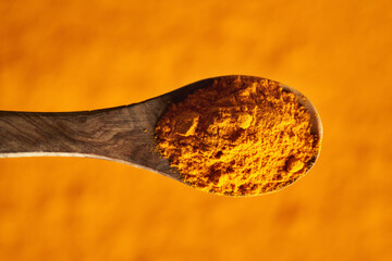 Turmeric root powder on a wooden spoon