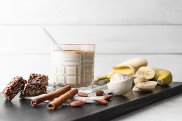 Glass with protein drink, healthy milkshake smoothie on wooden board with bananas, protein powder...