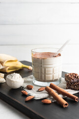 Glass with protein drink, healthy milkshake smoothie on wooden board with bananas, protein powder...