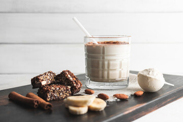 Glass with protein drink, healthy milkshake smoothie on wooden board with bananas, protein powder...