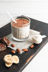 Glass with protein drink, healthy milkshake smoothie on wooden board with bananas, protein powder...
