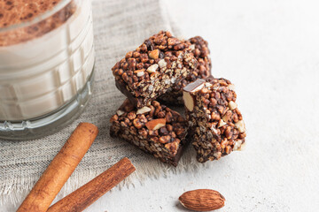 Pieces of chocolate protein bar, glass with protein drink, milkshake smoothie on white table