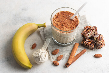 Glass with protein drink, healthy milkshake smoothie on white table with bananas, protein powder in...