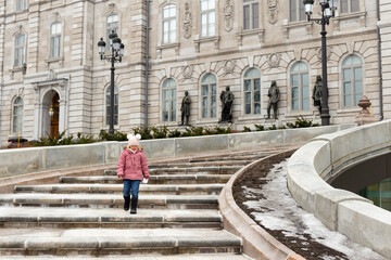 Little girl in winter clothes walking down the stairs of the 1886 Parliament Building, Quebec City, Quebec, Canada