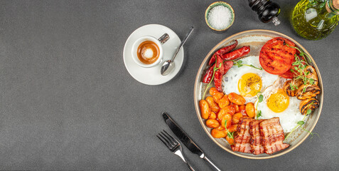Traditional full English breakfast with fried eggs, sausages, beans, mushrooms, grilled tomatoes and bacon served on grey table. top view. copy space for text