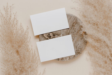 Empty mockup business card on marble stand and pampas grass. Aesthetic paper card template for...