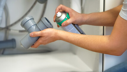 Close up of plumbers hands repair plumbing pipes sewerage using silicone lubricant. Replacement of...