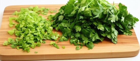 A cutting board with neatly chopped vibrant green vegetables, including fresh green parsley leaves, arranged for cooking or meal preparation.