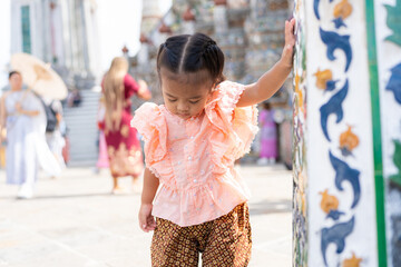 Toddler kindergarten girl wear Thai style costume travel in Wat Arun buddhist temple sightseeing...
