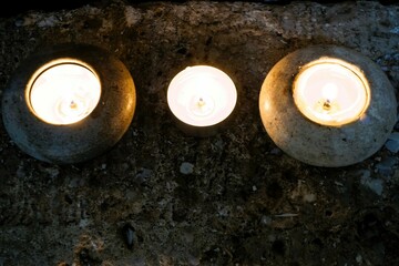 Drei kleine brennende Teelichter auf altem grauen Steinboden in Klosterkirche 