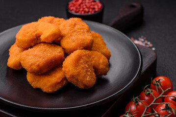 Delicious fresh crispy chicken nuggets on a dark concrete background