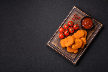Delicious fresh crispy chicken nuggets on a dark concrete background