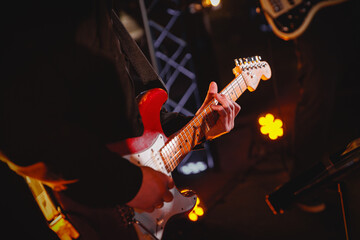 The guitarist plays with group on the stage,