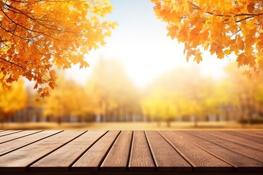 An empty wooden table top against the background of warm autumn leaves.