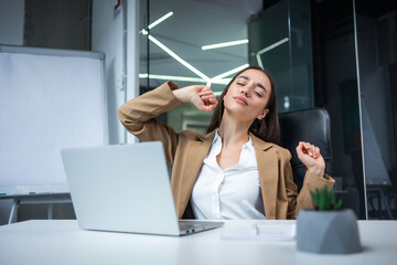 Relaxed office worker woman stretching hands and body taking break from work on laptop. Joyful freelancer copywriter girl happy with task done at workplace in coworking space