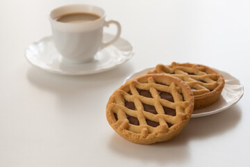 Mini crostate al cioccolato con tazzina bianca di caffè su tavolo bianco