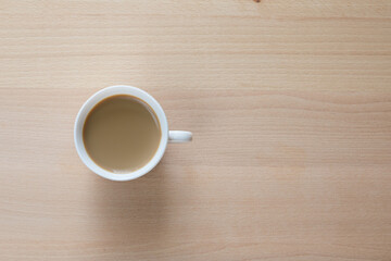 Tazzina bianca con caffè e piattino su tavolo di legno