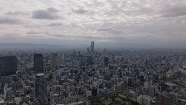 Metropolis from height. Fly above buildings in urban borough in large city in flat landscape. Osaka, Japan