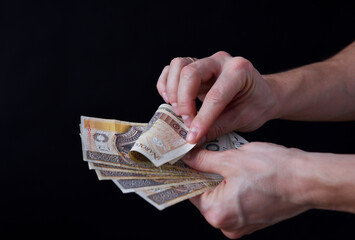Mezczyzna trzymajacy polskie banknoty, gotowka. Plik pieniedzy w dloni.