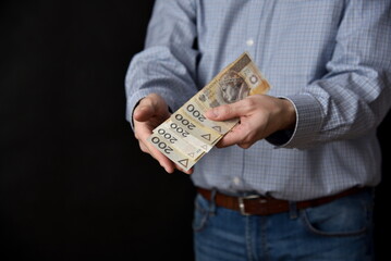 Mezczyzna trzymajacy polskie banknoty, gotowka. Plik banknotow 200 zlotych. - obrazy, fototapety, plakaty